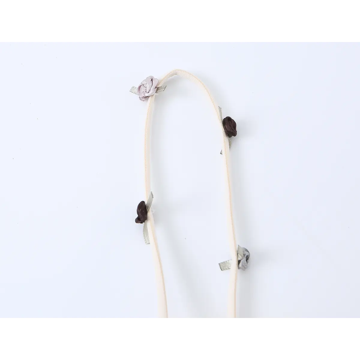 Close-up of the dress's thin strap, featuring delicate rose appliqus in purple, brown, and silver tones.