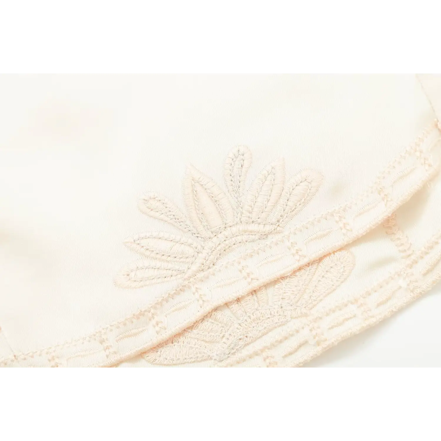 Close‑up of floral embroidery stitch work on cream satin corset top