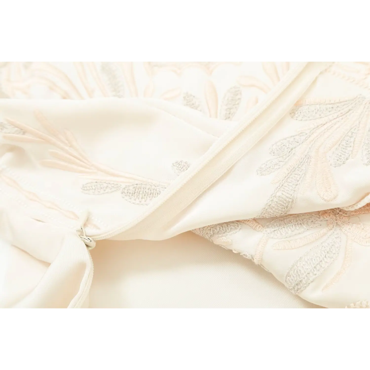 Close‑up view of cream embroidered corset top, hidden side zipper and floral embroidery fabric detail