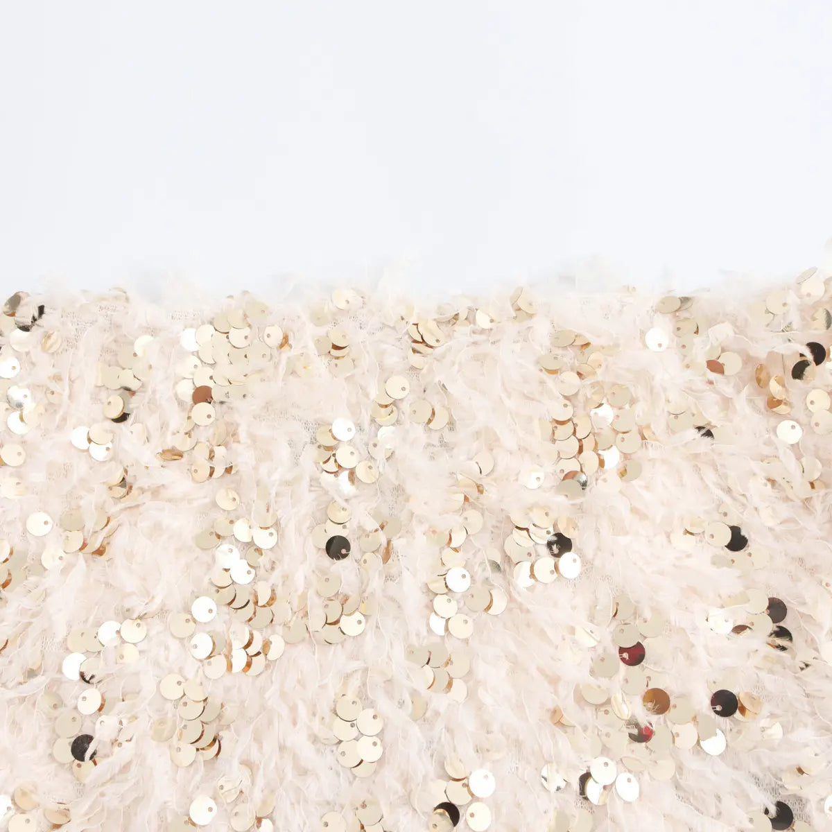 Close‑up fabric texture cream fluffy feather mixed with gold and champagne sequins party garment material