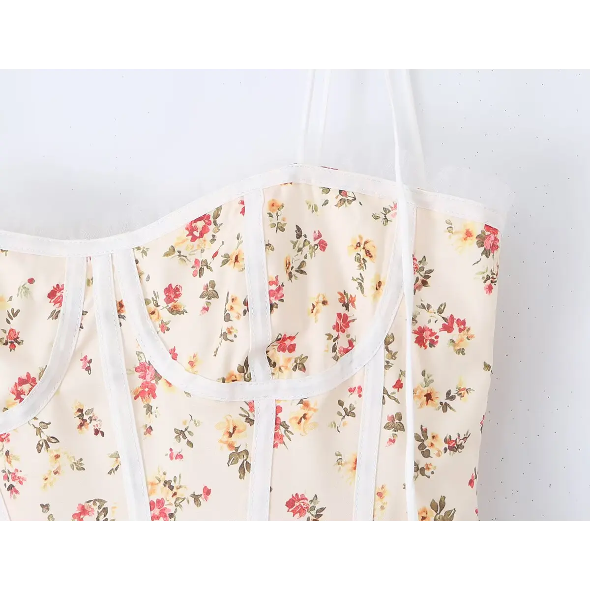Close-up of the corset-style bodice and floral print on the cream cami dress
