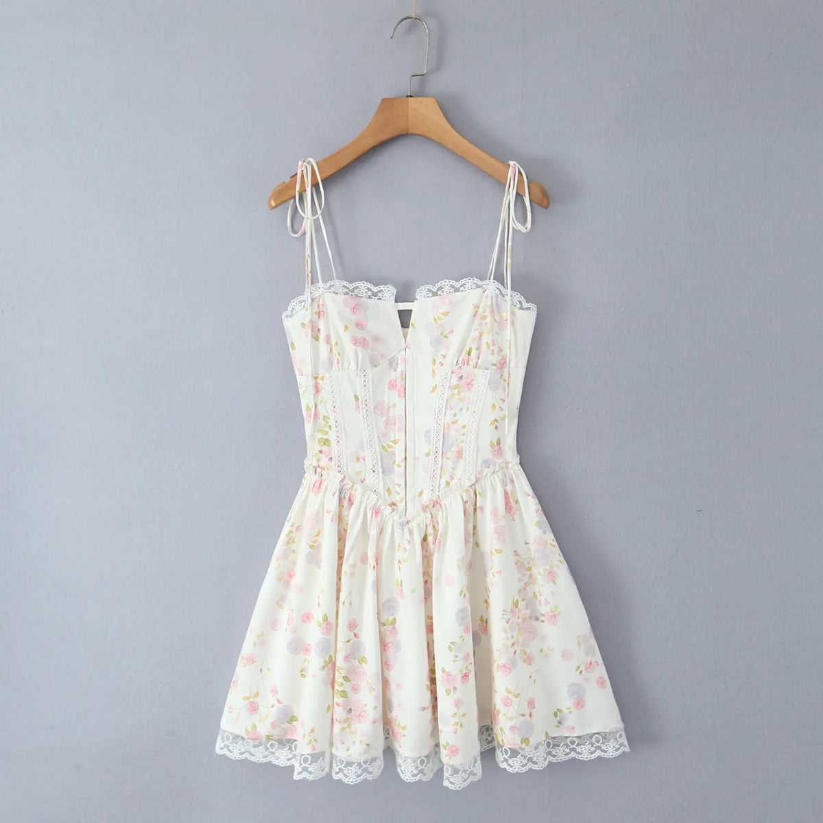 Women cream floral print cami mini dress with tie straps, hanging on wooden hanger, front view