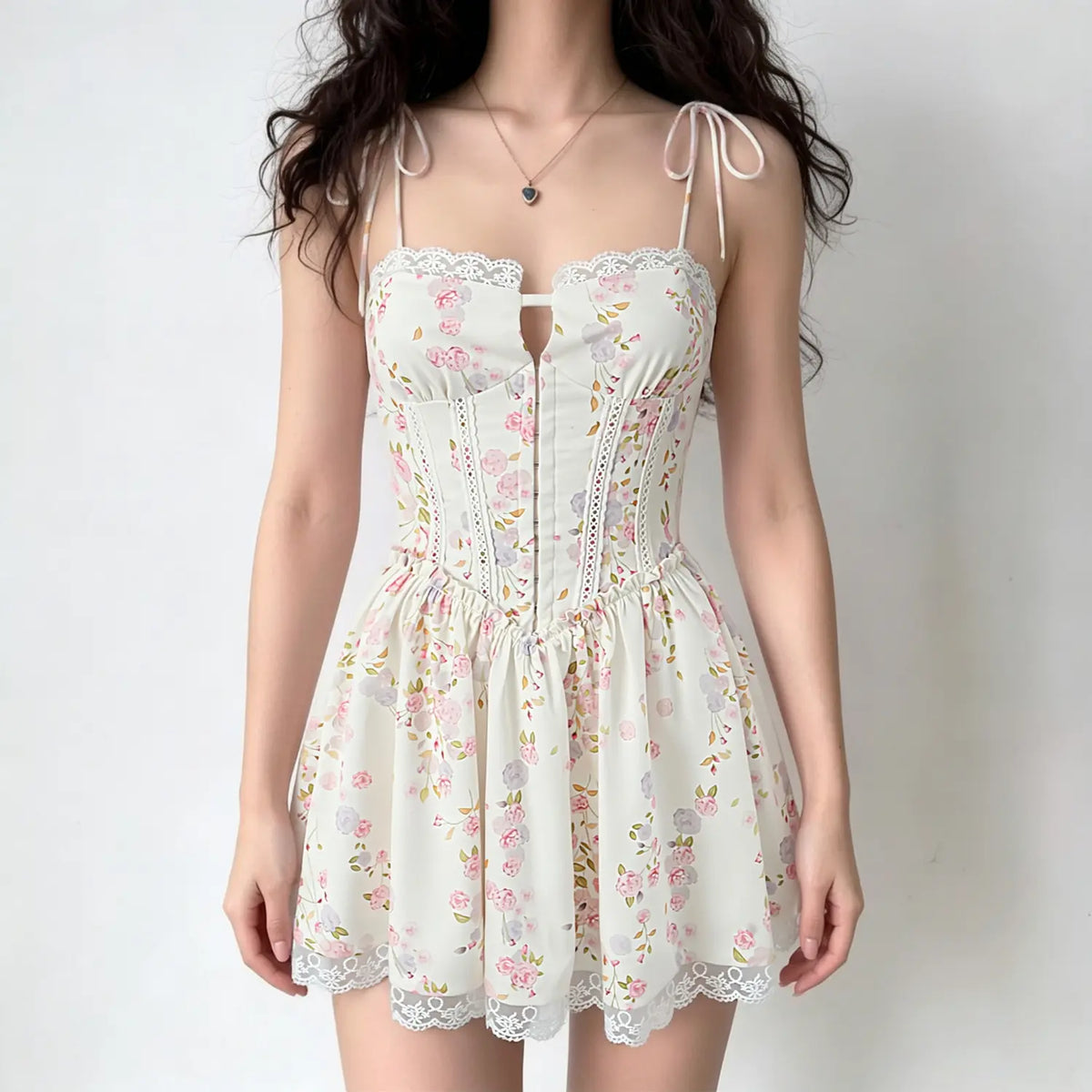 Model wearing cream floral print corset cami mini dress, tie shoulder straps, lace trim hem, coquette summer outfit