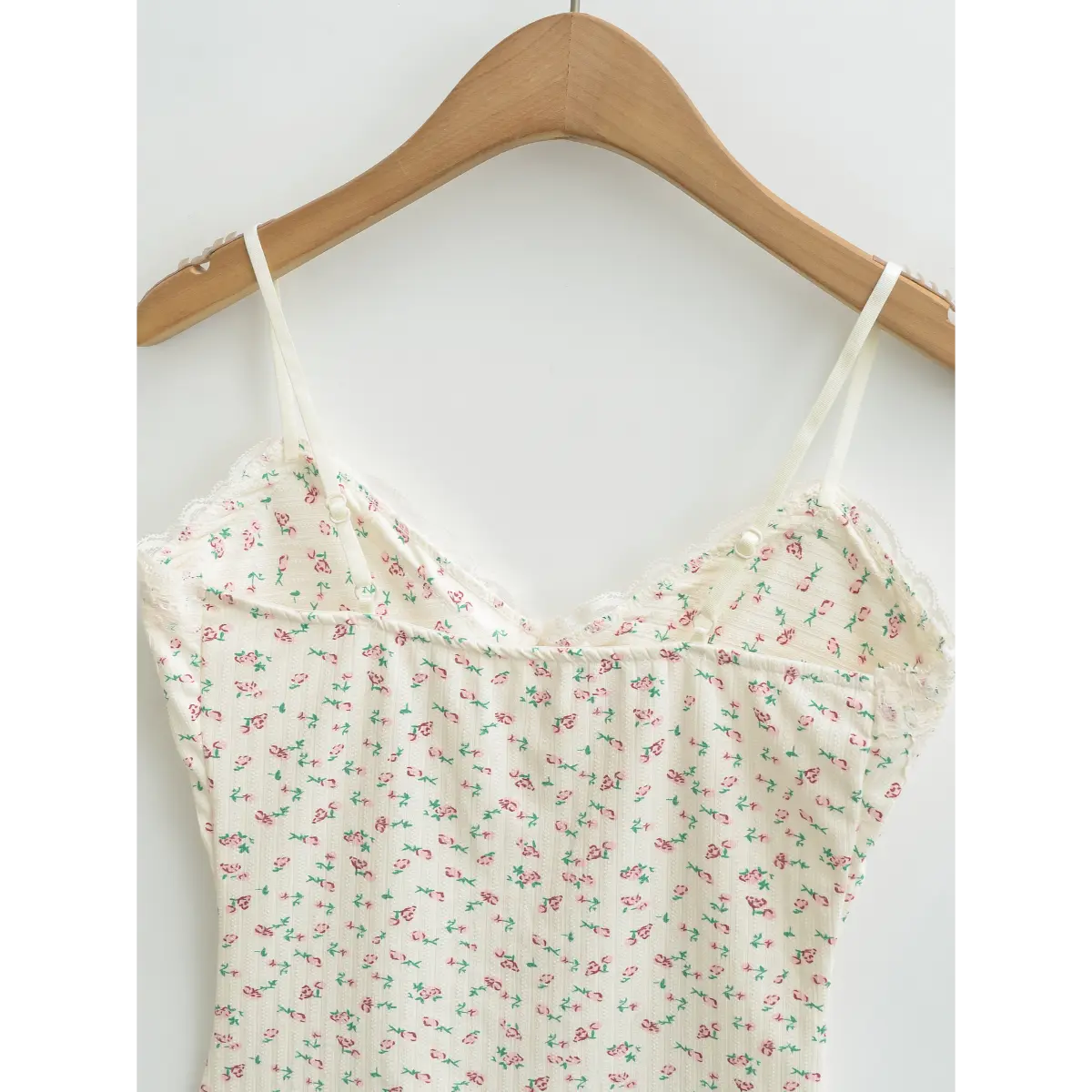 Close-up of the back of a cream floral cami top, showing the adjustable straps and lace-trimmed neckline.
