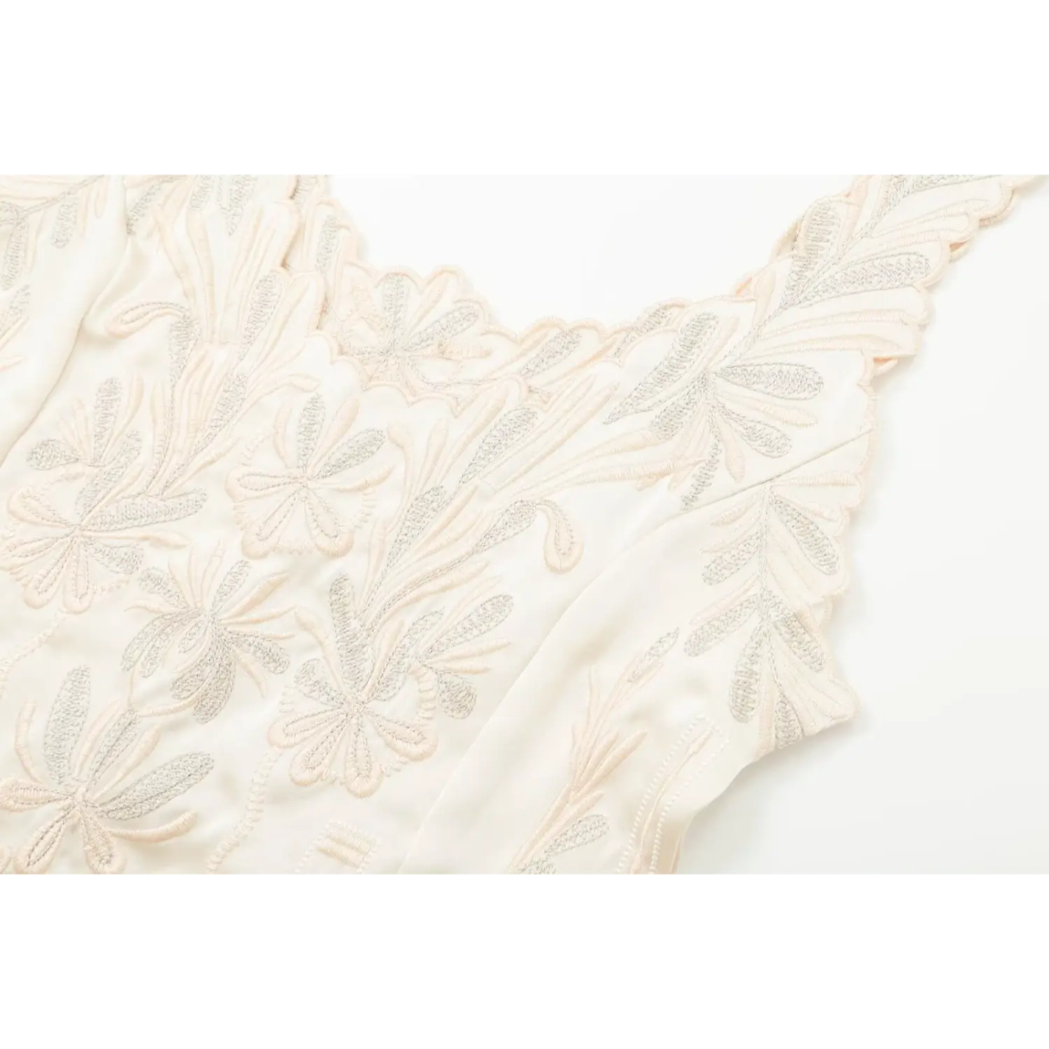 Close‑up view of two‑tone floral embroidery across bust of cream camisole top