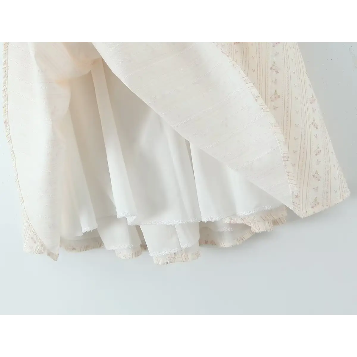 Close-up of the layered skirt hem and inner lining on the cream floral halter dress