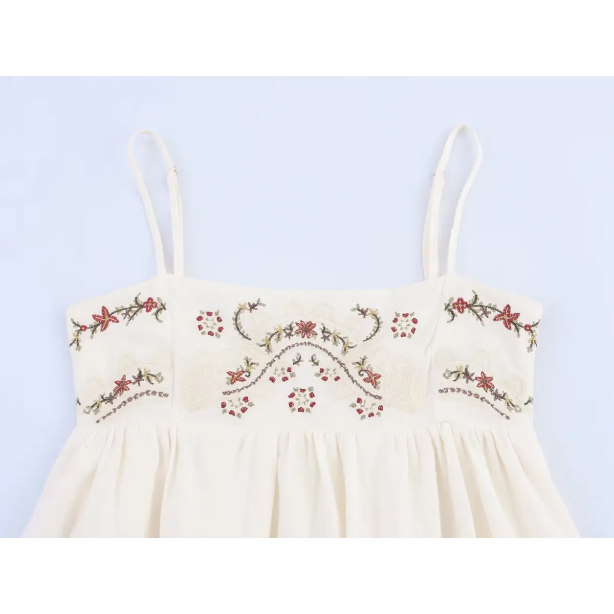 Full front studio shot of the cream embroidered spaghetti strap dress, showing the bodice pattern.