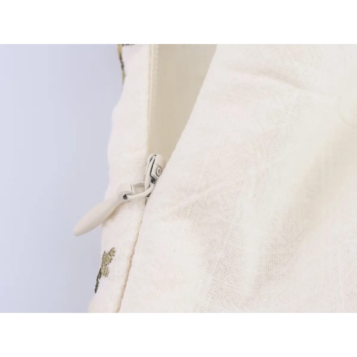 Close-up of the hidden side zipper on the cream floral embroidered dress.