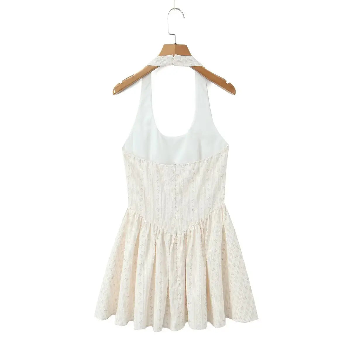 Cream floral halter dress hanging on wooden hanger, showing back silhouette and halter straps