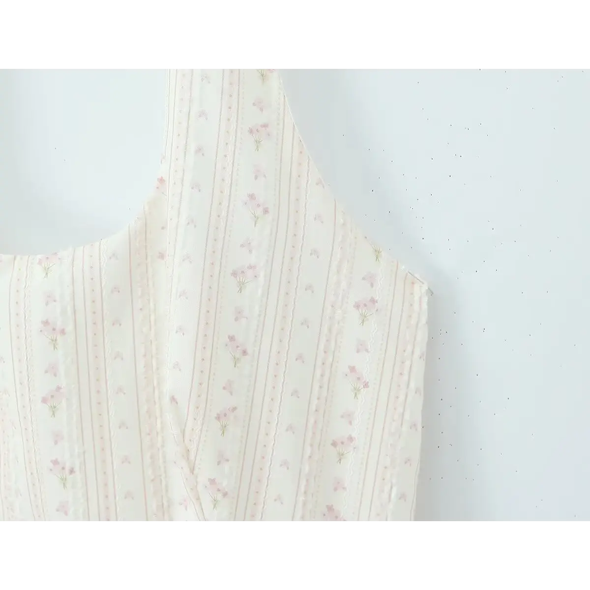 Close-up of the eyelet embroidery and floral pattern on the cream halter dress bodice