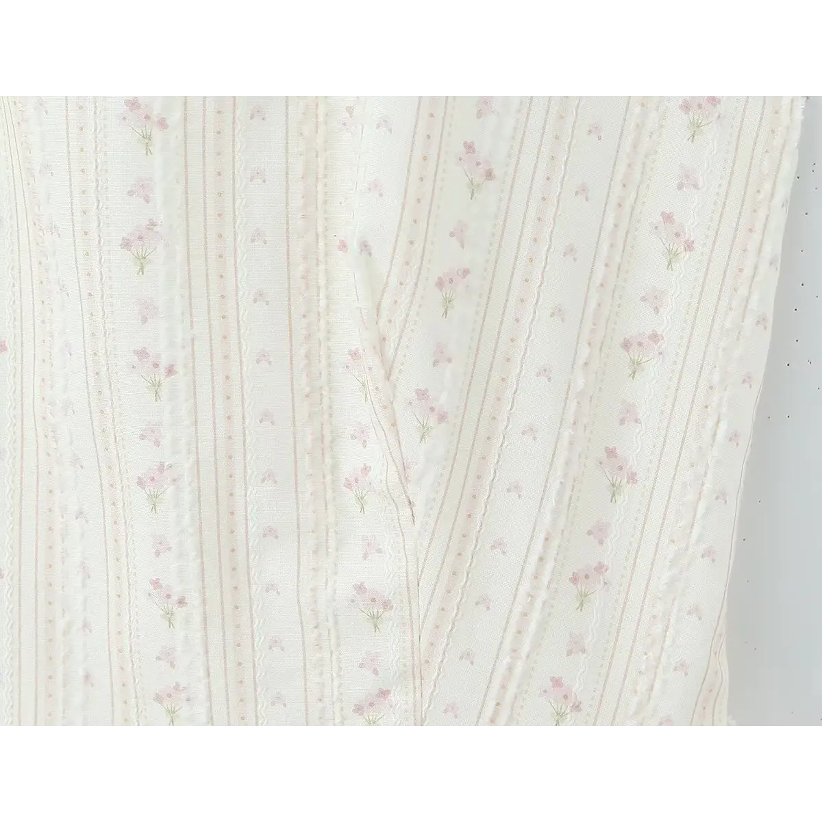 Close-up of the delicate floral print and eyelet embroidery on the cream halter dress