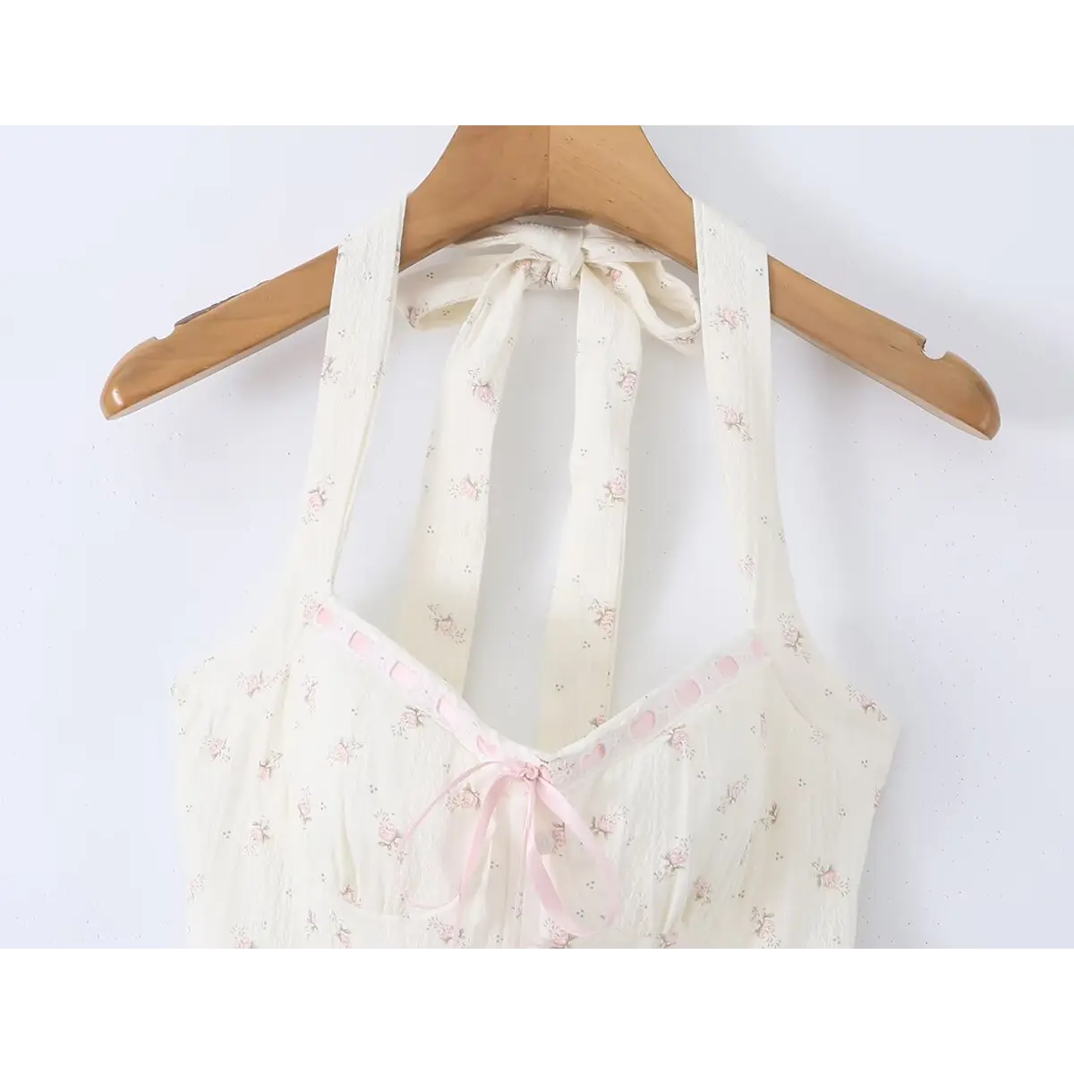 Cream floral print halter dress hanging on wooden hanger, showing halter straps and neckline detail