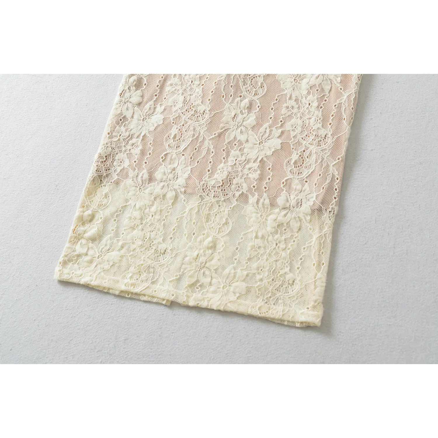 Flat detail of dress bottom hem, full floral lace pattern, finished scalloped lace edge