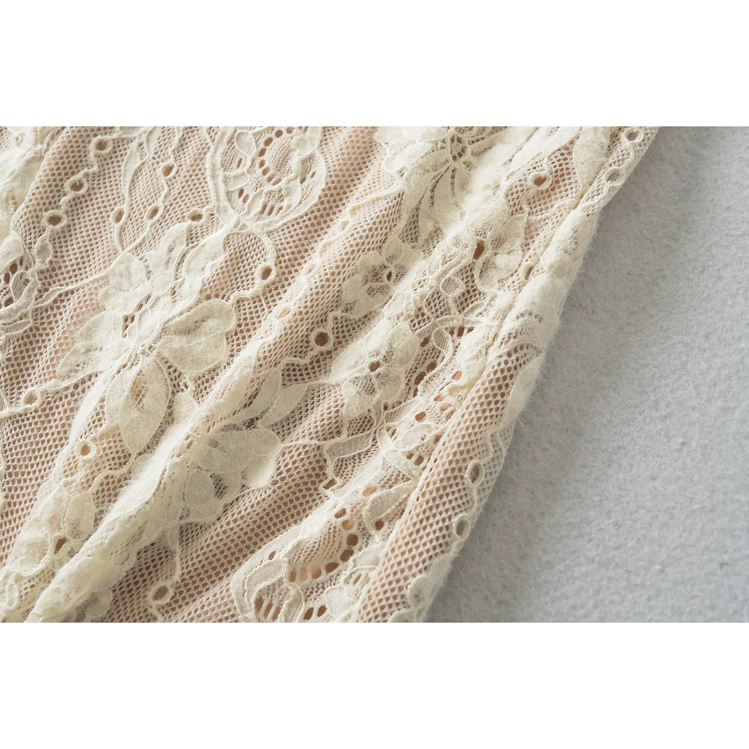 Close‑up detail of cream floral lace midi dress side seam, intricate flower lace mesh stitching against nude lining