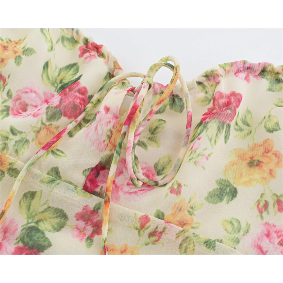 Close-up of the front drawstring tie and gathered bust detail on the cream floral dress.