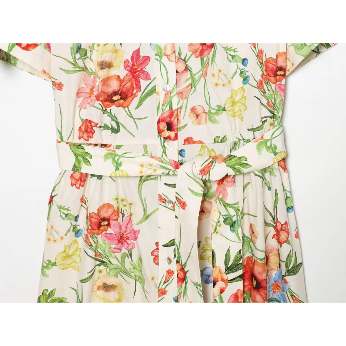 Close-up of gathered waist seam and wrapped self-tie belt on cream floral shirt midi dress, showing fabric draping