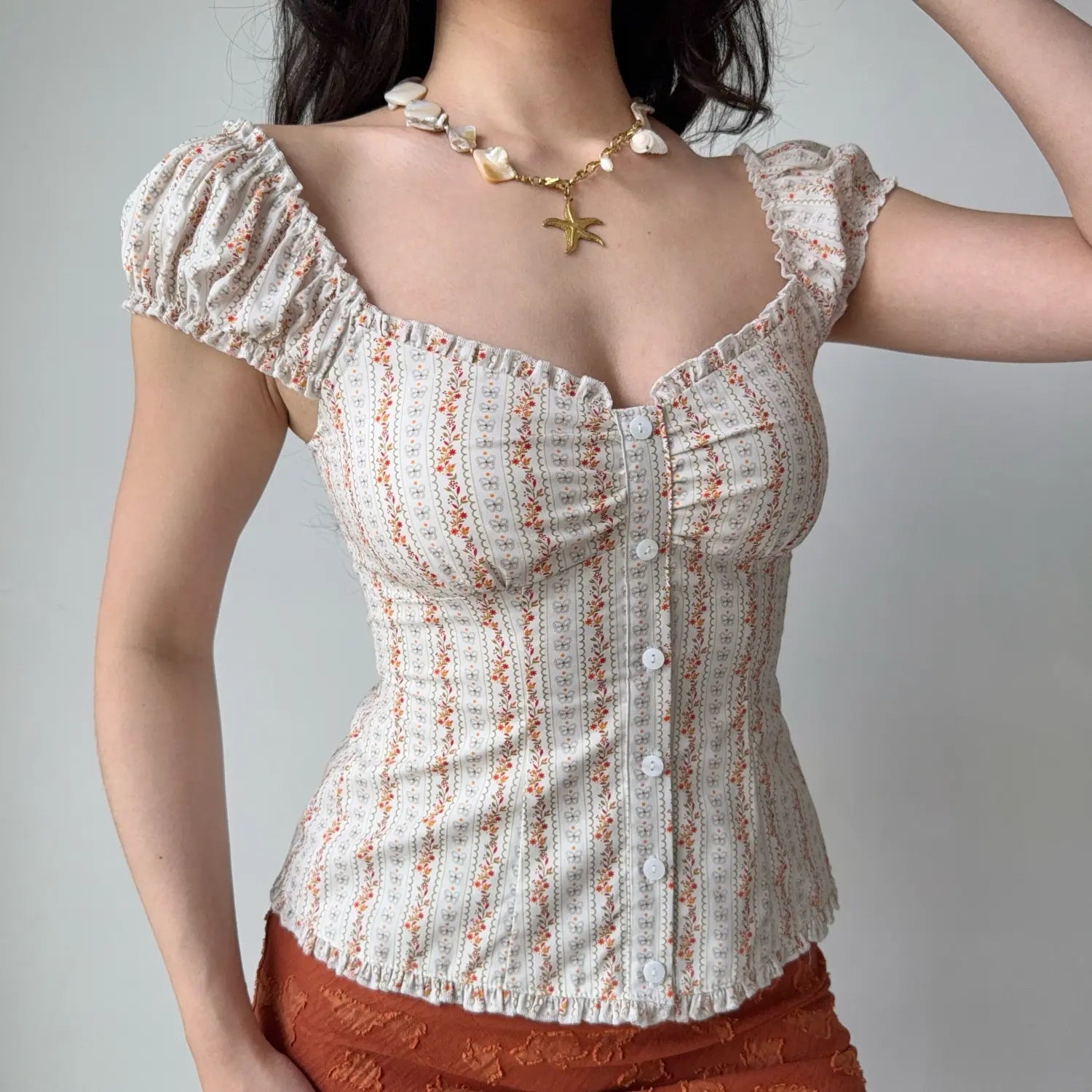 Front lifestyle shot on model of cream floral striped blouse, square neck, ruched bust, short elastic puff sleeves