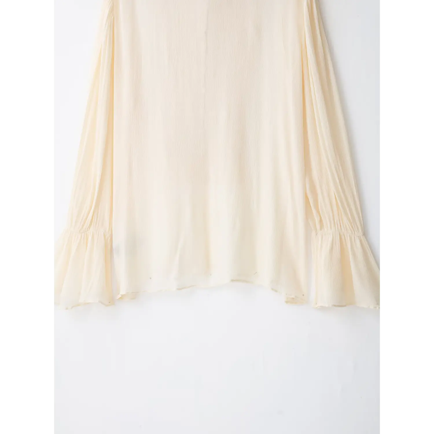 Full back bottom view of cream textured chiffon long sleeve blouse