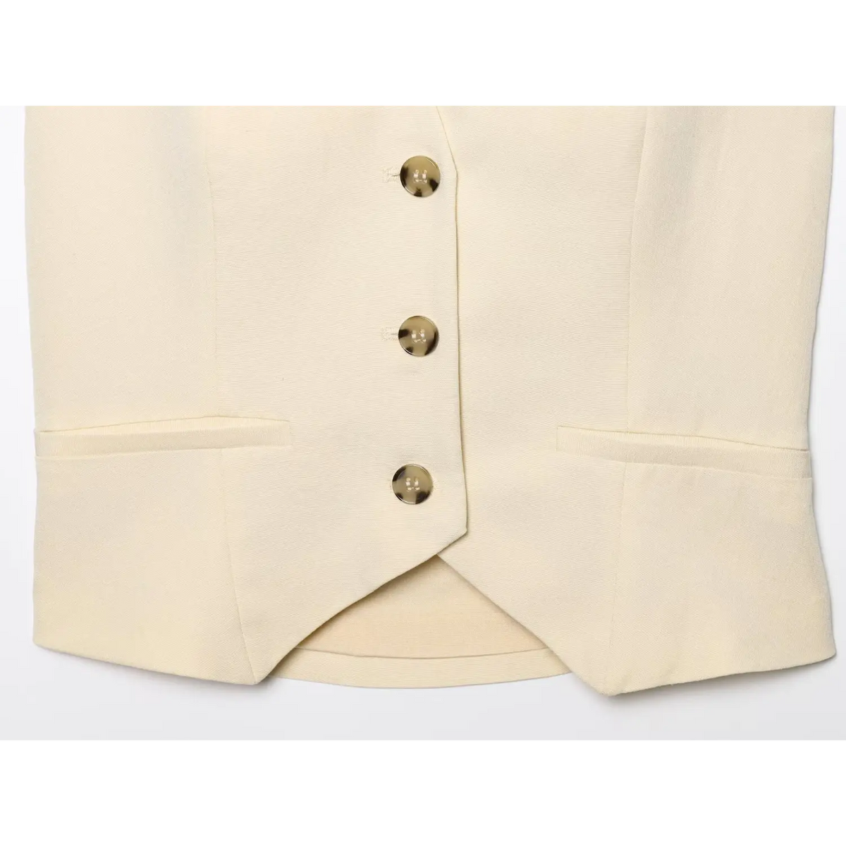 Close-up of pointed hem, three buttons and welt pockets