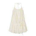 Flat lay front view of cream halter tiered mini dress, halter tie‑back neck, elastic gathered bust, side drawstring waist, flowy ruffle hem, isolated white background