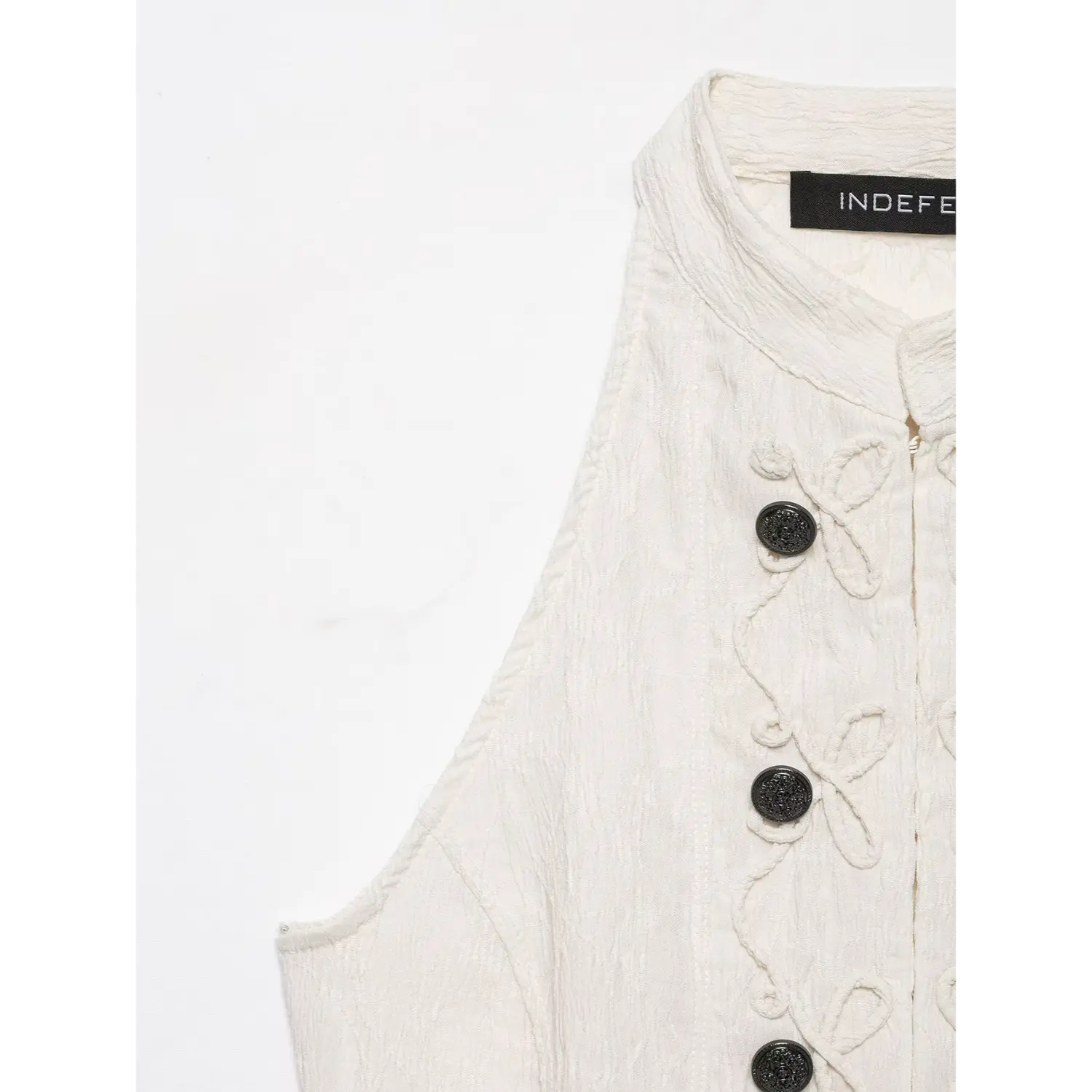 Close‑up shot collar and shoulder part cream halter top, textured fabric and brand label view
