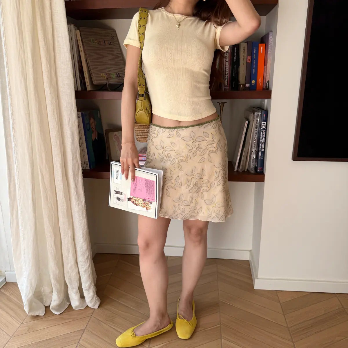 Bookcase indoor lifestyle shot cream textured hollow knit cropped short sleeve top with floral skirt
