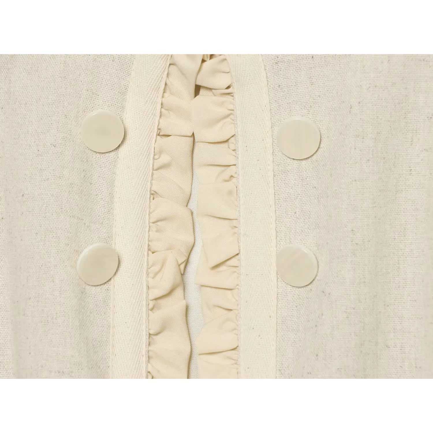 Close‑up of double row round buttons and center front ruffle trim on cream cropped jacket