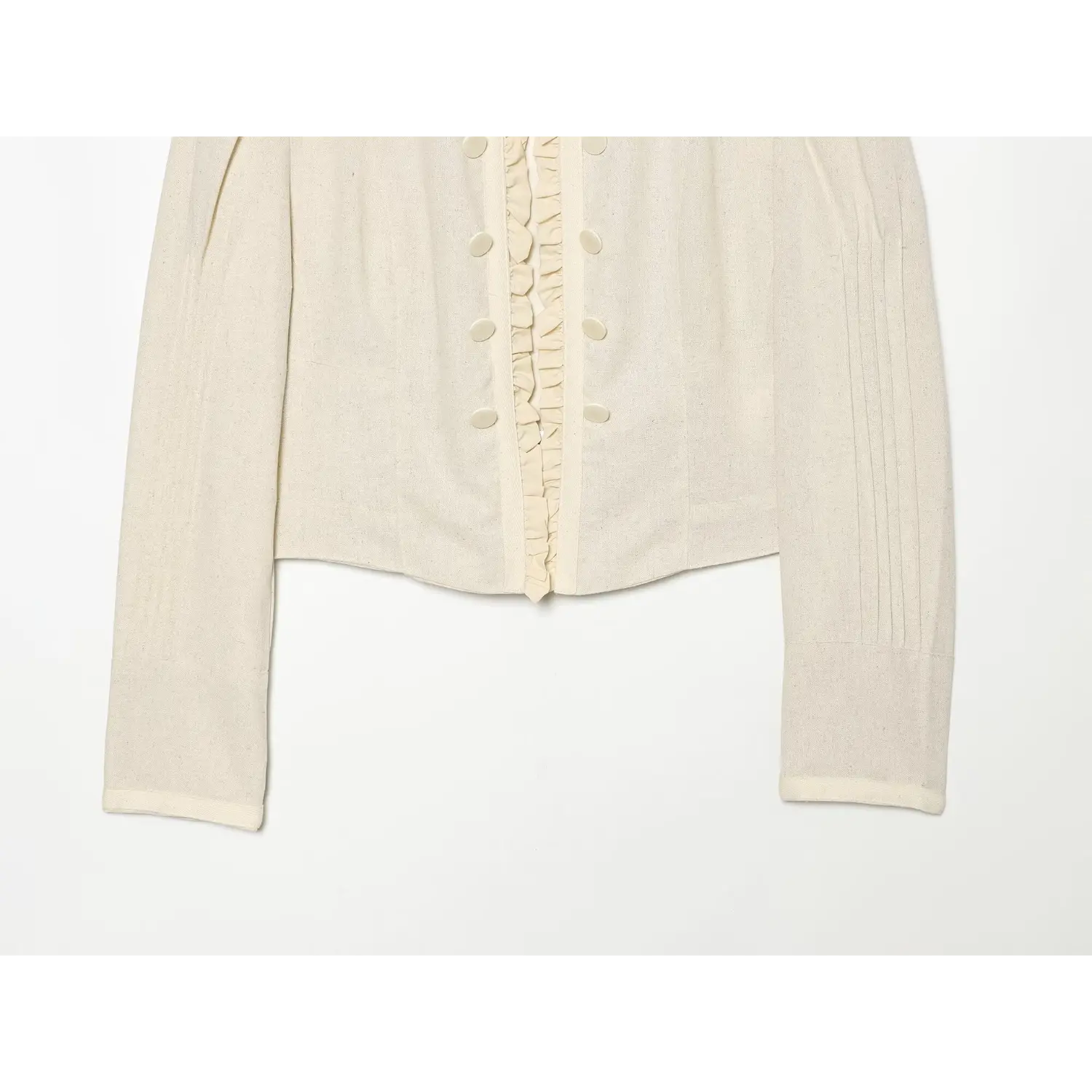 Flat lay partial shot, cream cropped jacket lower hem and long sleeves with vertical sleeve pleats