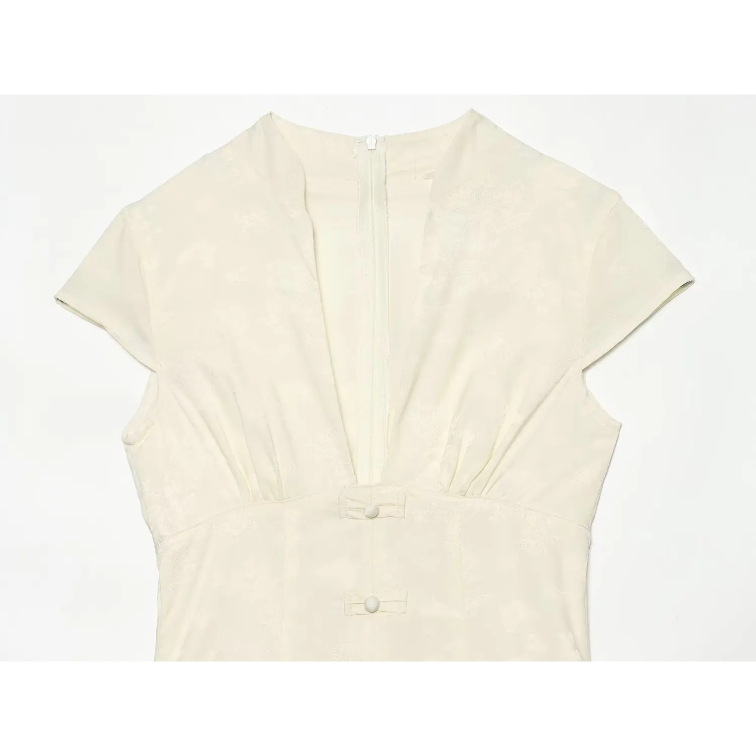 Close-up deep v neck and bodice of cream floral jacquard dress, cap sleeve gathered bust and vertical frog buttons