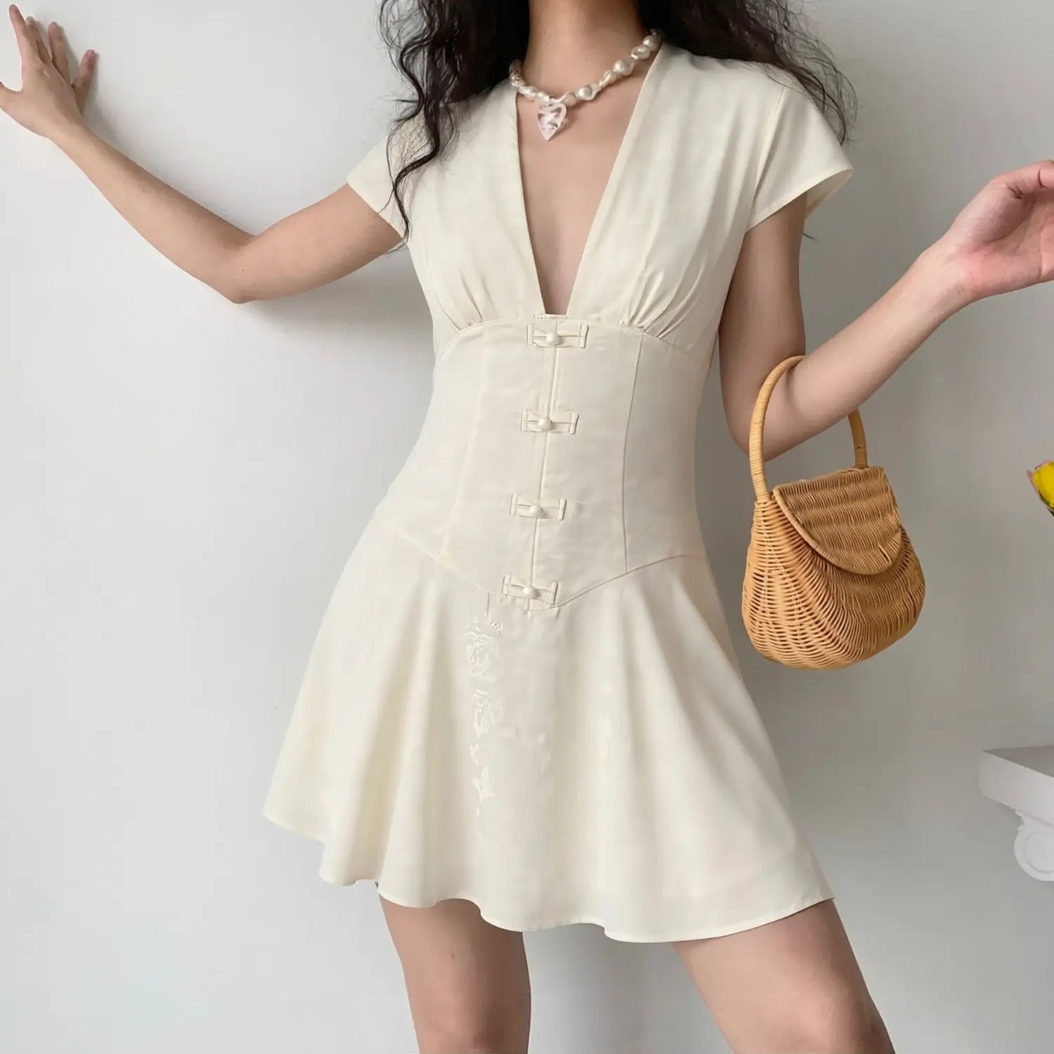 Lifestyle model shot cream white jacquard mini dress, deep v cap sleeve corset waist frog buttons casual feminine outfit