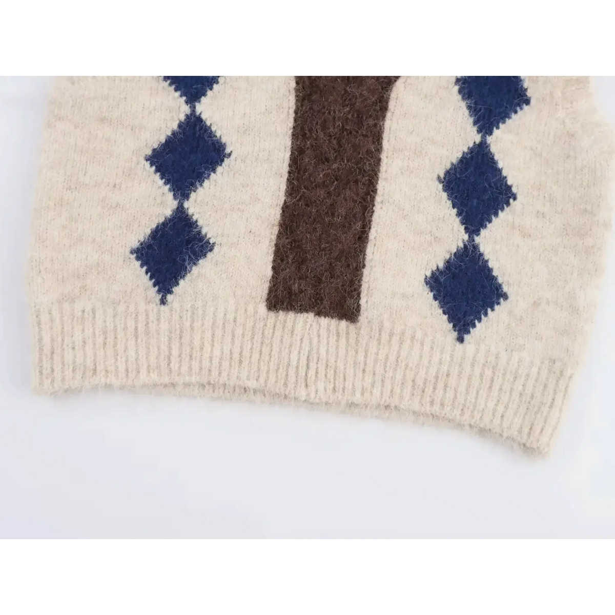 Bottom hem detail of cream argyle knit vest, navy blue diamond jacquard and fuzzy knit texture