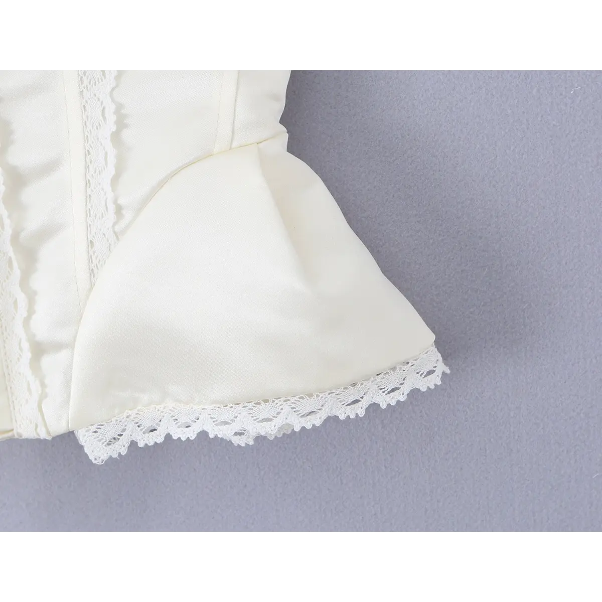 Close-up of the peplum-style hem and lace trim on the cream corset bustier