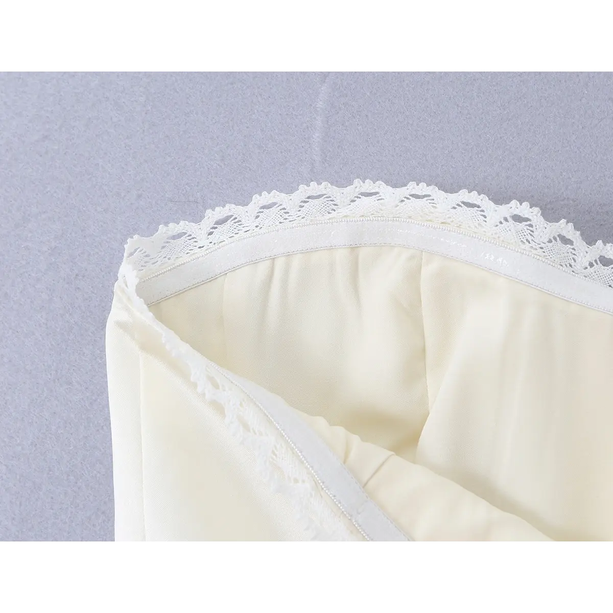 Close-up of the lace-trimmed neckline and inner lining on the cream corset bustier