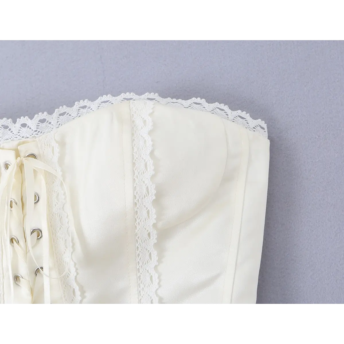 Close-up of the delicate lace trim and boning structure on the cream corset bustier