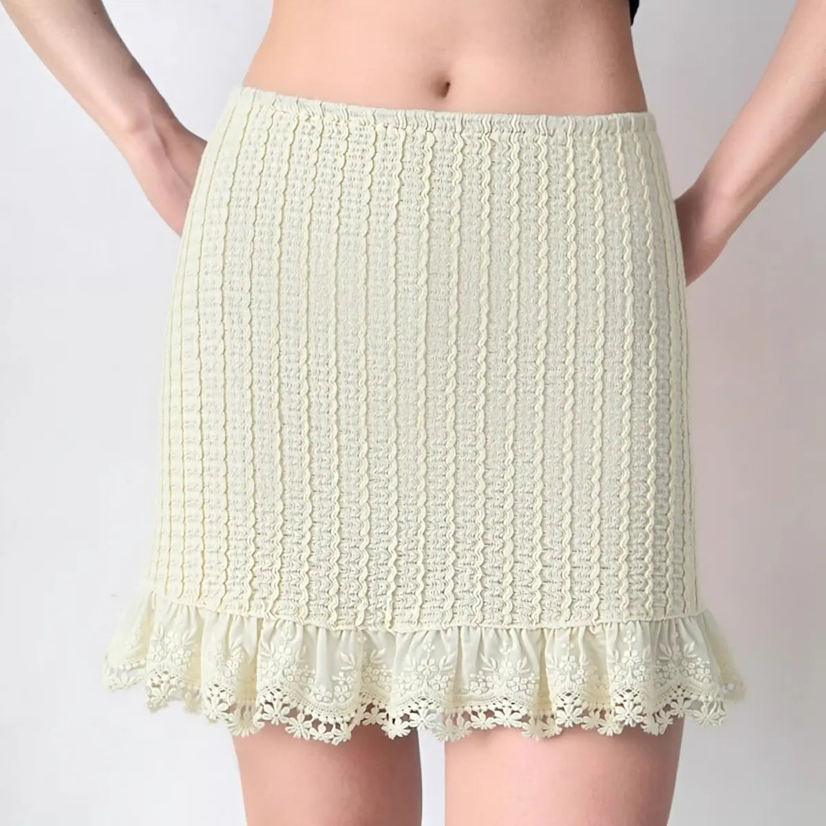 Woman wearing cream lace crochet mini skirt with ruffled hem, front view