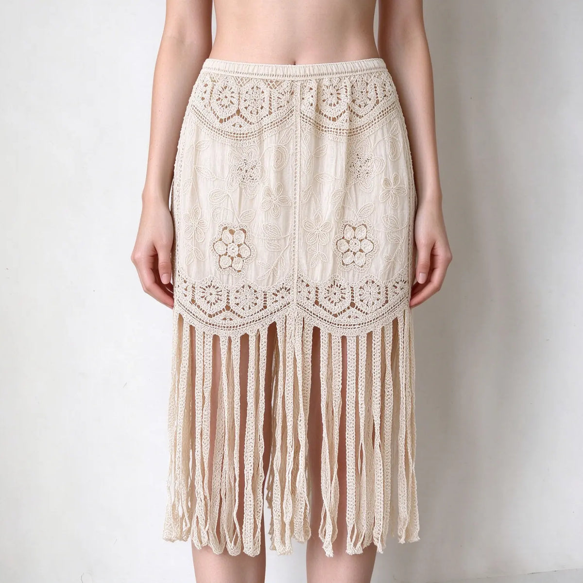 Model wearing cream boho midi skirt, floral crochet lace embroidery, elastic waist, long fringe tassel hem, loose fit, plain white background
