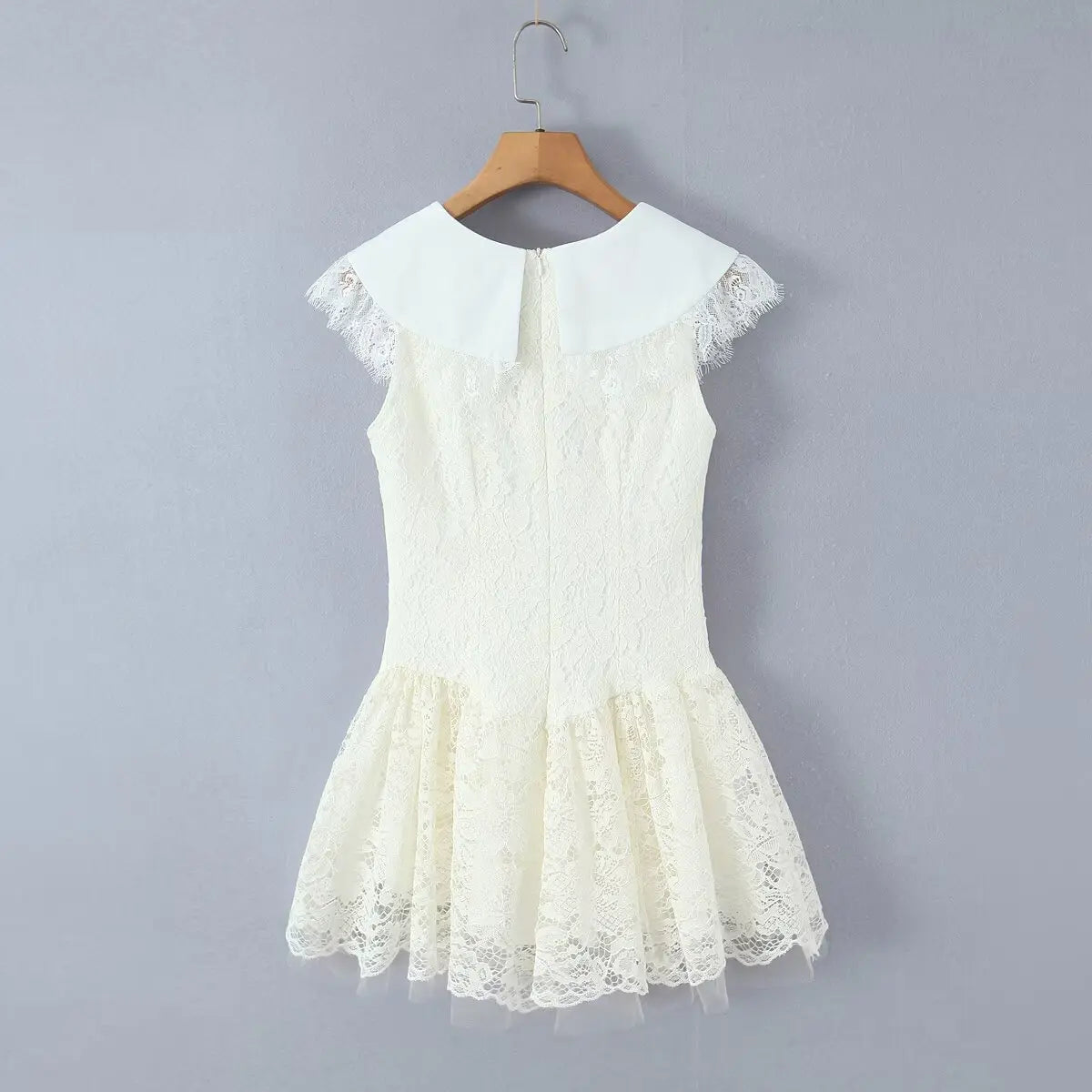 Back view of a cream lace mini dress, showing the center-back zipper, large flat collar, cap sleeves with frayed lace, and the flared lace skirt.