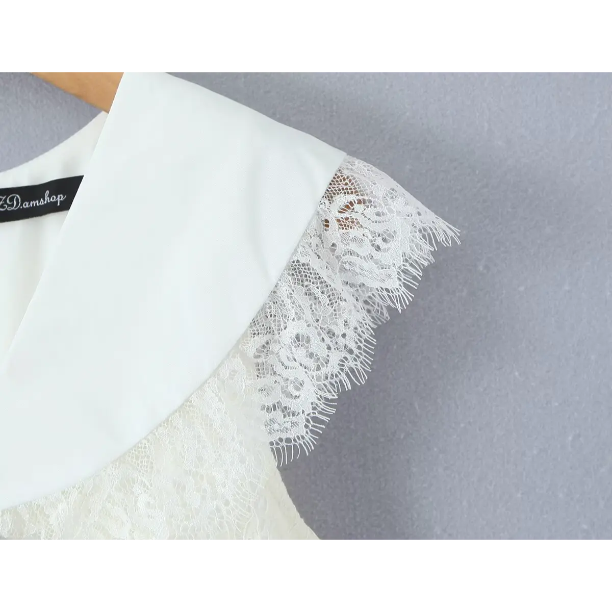  Close-up of the collar and cap sleeve on a cream lace dress, showing the contrast between the smooth collar fabric and the frayed, floral lace trim.