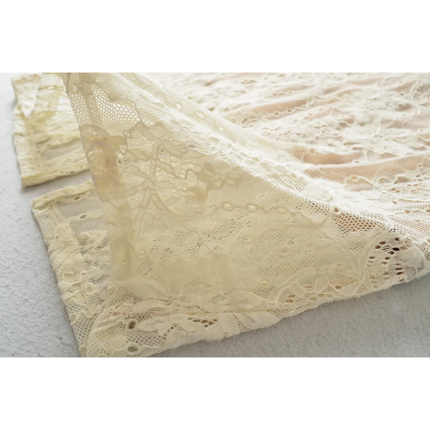 Flat detail of dress bottom hem, full floral lace pattern, finished scalloped lace edge