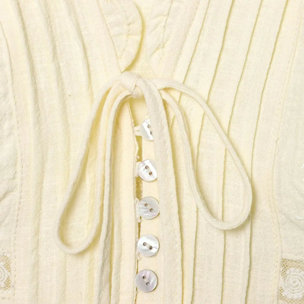 Full view of the cream bustier top, showing the V-neck, ruffled edge, lace/embroidery details, and overall silhouette