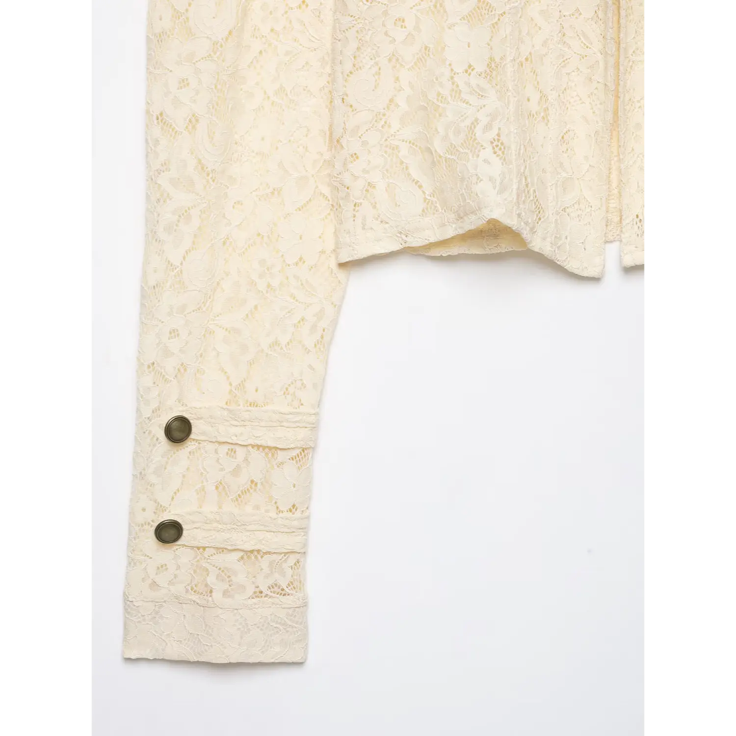 Close‑up shot of cream lace jacket sleeve cuff, double antique metal buttons, floral lace fabric detail