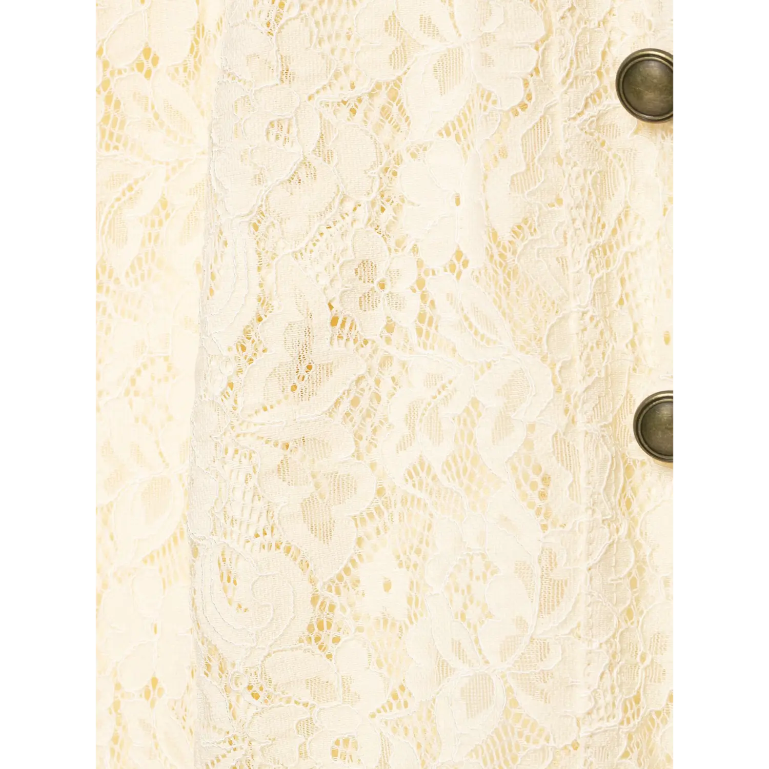 Close‑up texture shot of cream floral lace fabric from cropped lace jacket, partial antique metal buttons visible