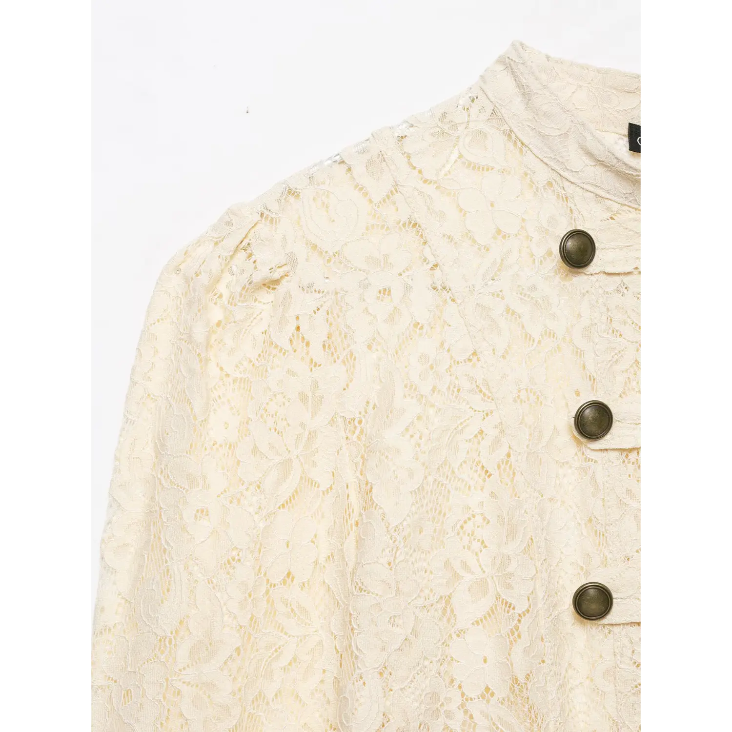 Close‑up detail of cream lace cropped jacket, stand collar, shoulder puff sleeve, antique brass buttons, floral lace texture