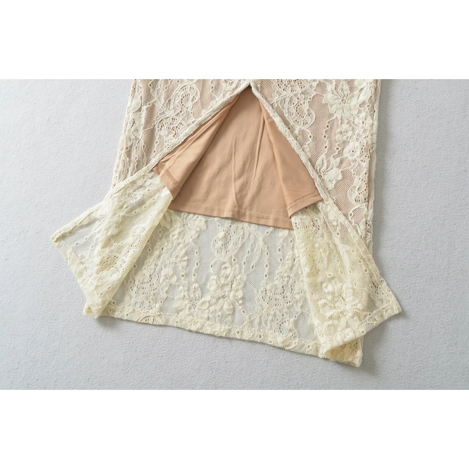 Flat shot showing open back hem slit, outer floral lace overlay and attached nude lining inside