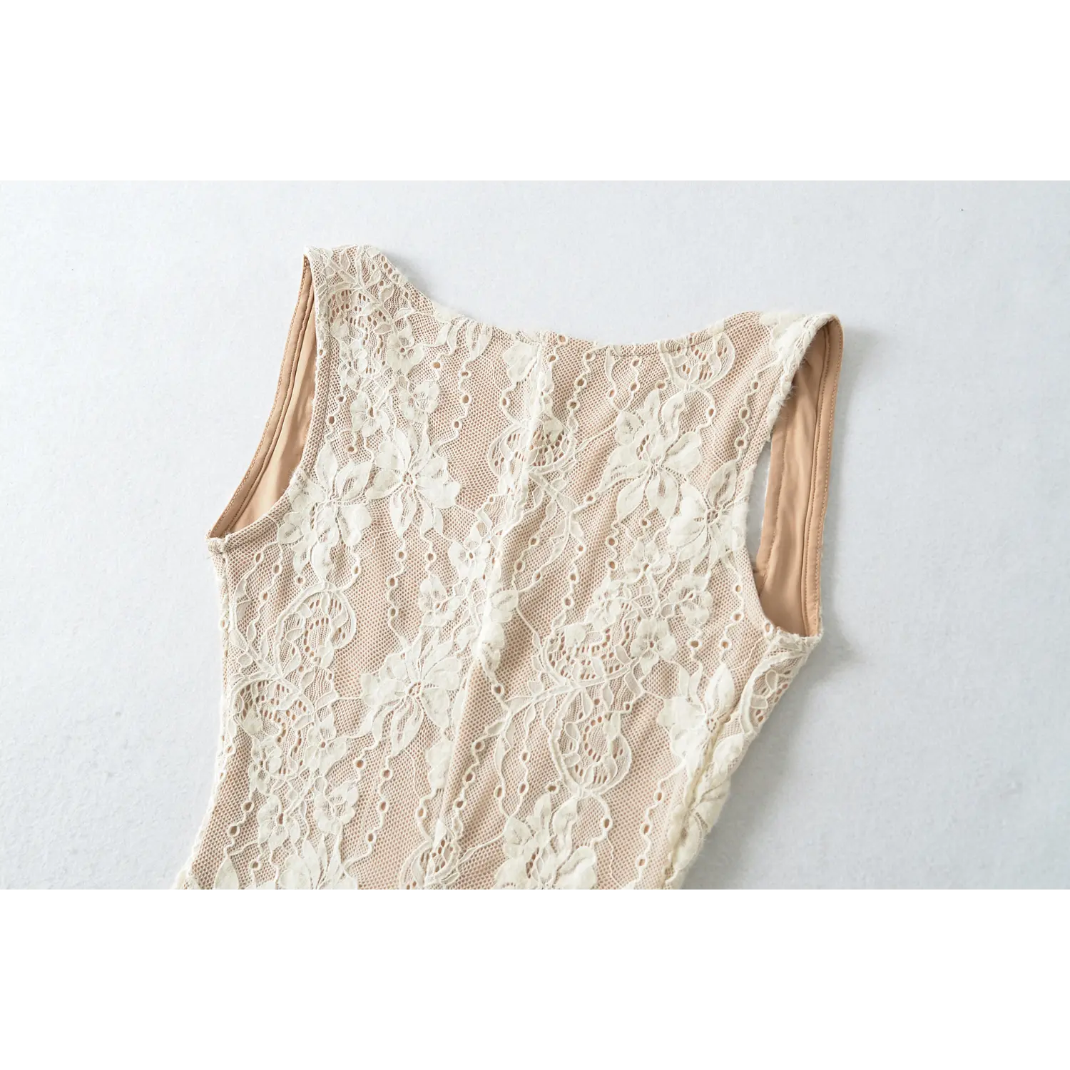 Close‑up view of cream lace dress back shoulder area, floral lace mesh fabric and armhole finished edge