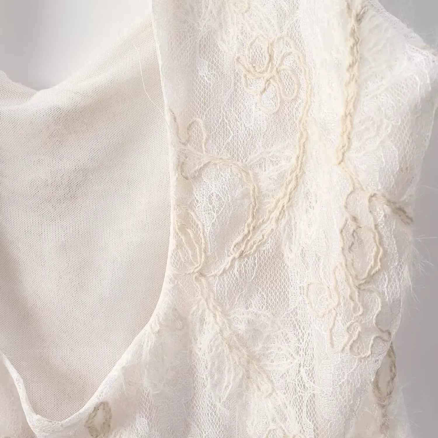 Macro view of cap sleeve armhole with floral embroidery on cream lace fitted top