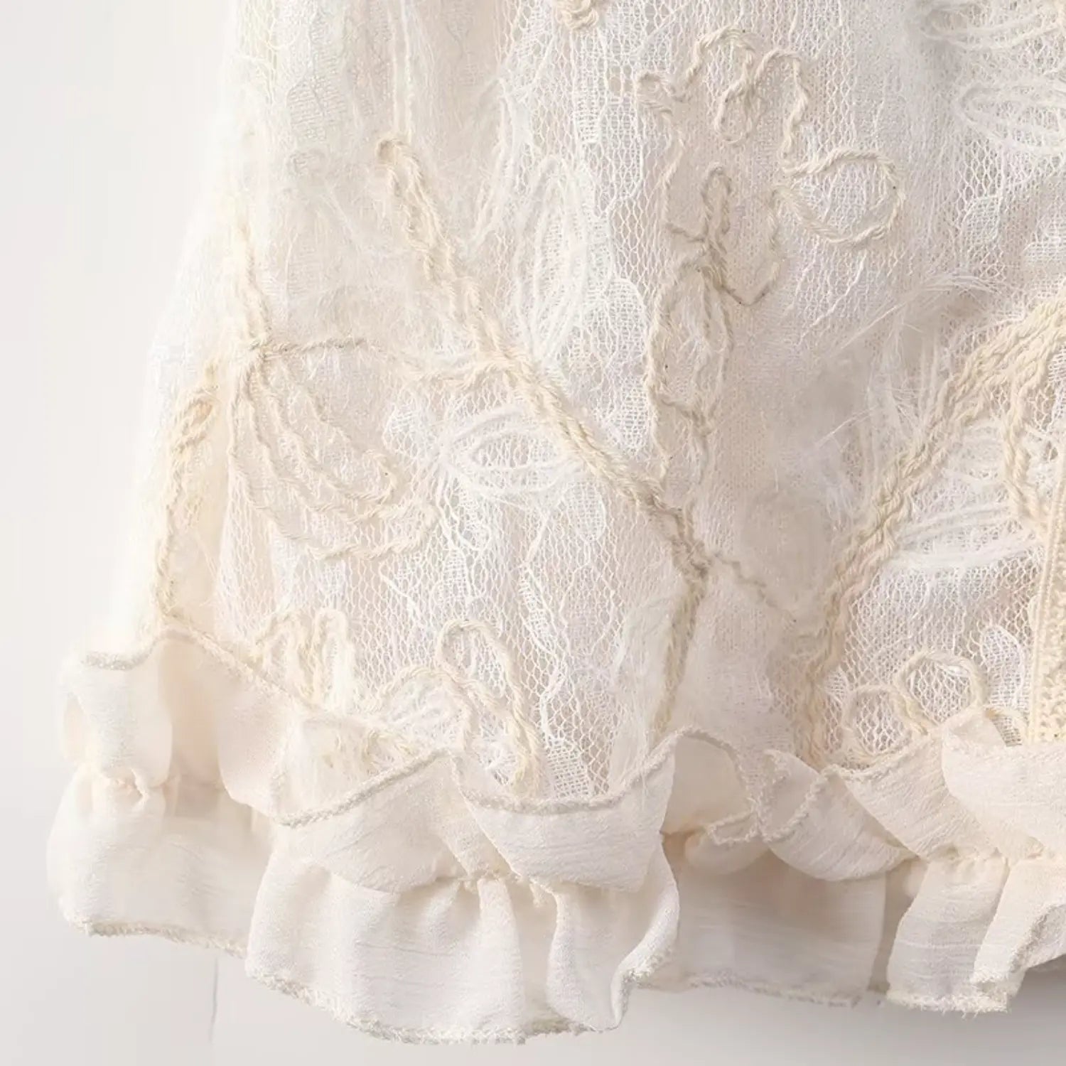 Close view of bottom ruffle hem and floral lace fabric for cream sleeveless blouse