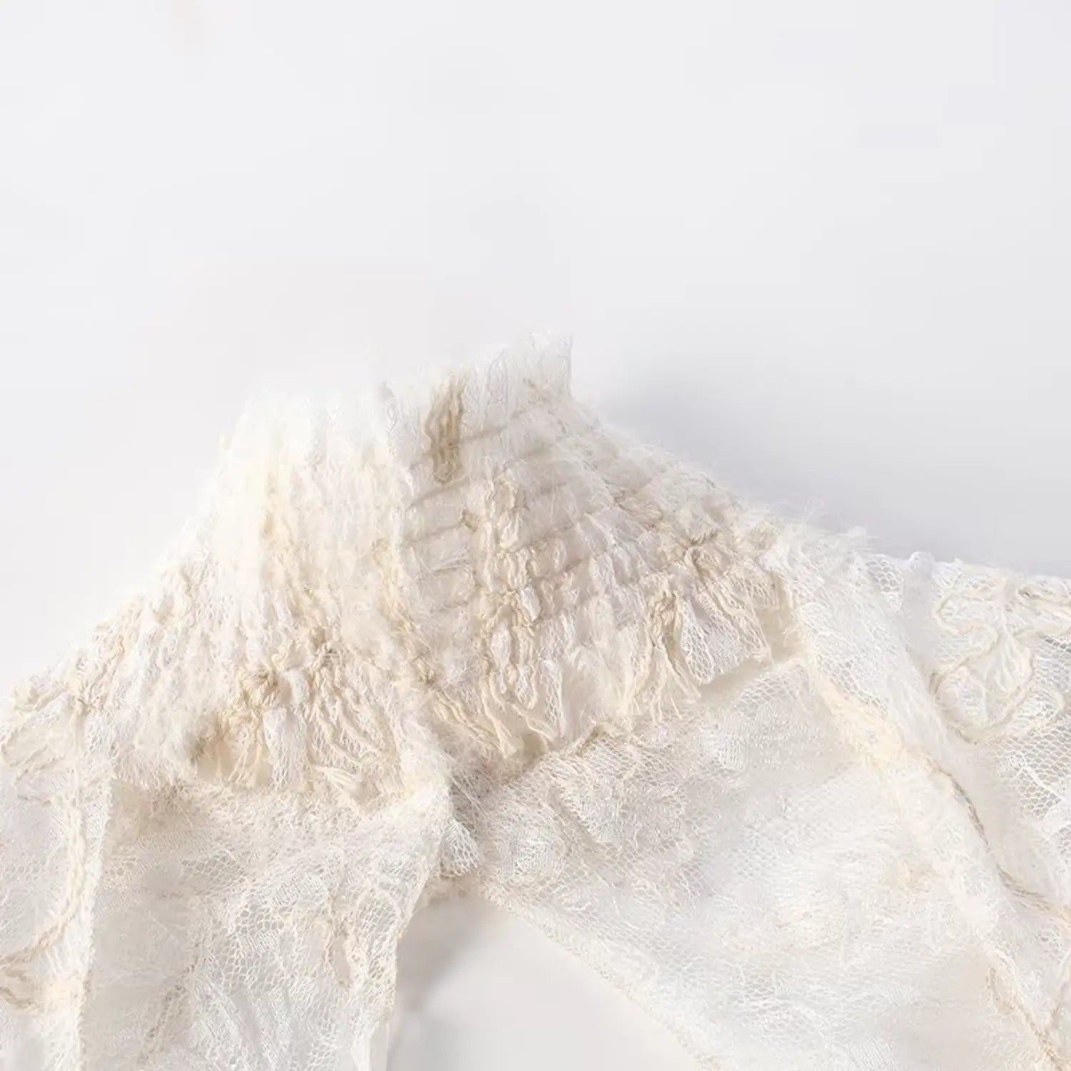 Close up of high smocked ruffle neck on cream embroidered lace sleeveless blouse