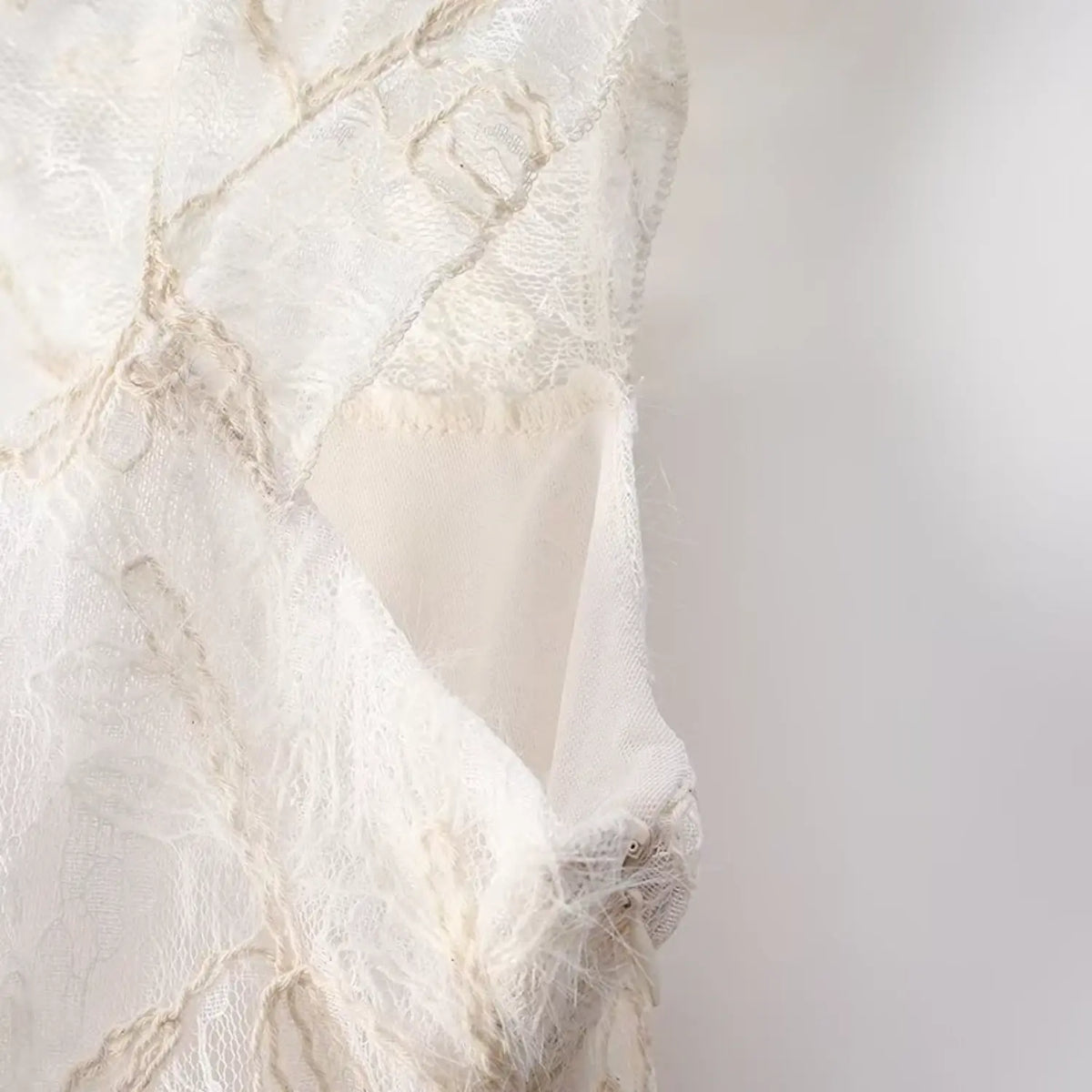 Close-up side view of cream floral lace sleeveless top, showing inner lining and embroidered lace texture