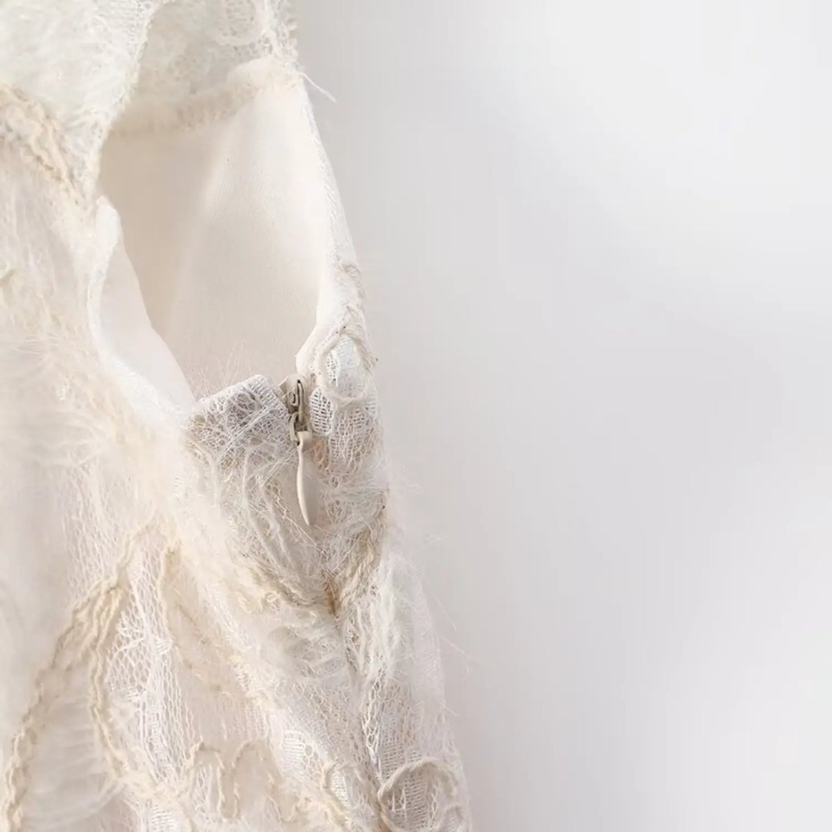 Macro shot of invisible side zipper on cream embroidered lace camisole, lace overlay and soft inner lining